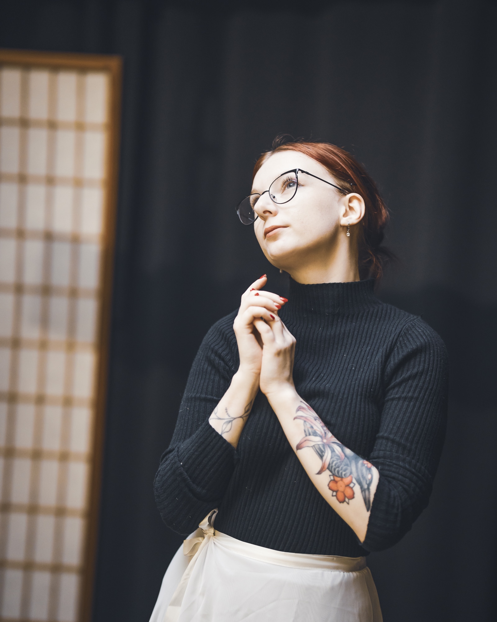 Myu z AKD v černém roláku a světlé sukni stojí v dojo prostoru s bambusovým pozadím během workshopu.