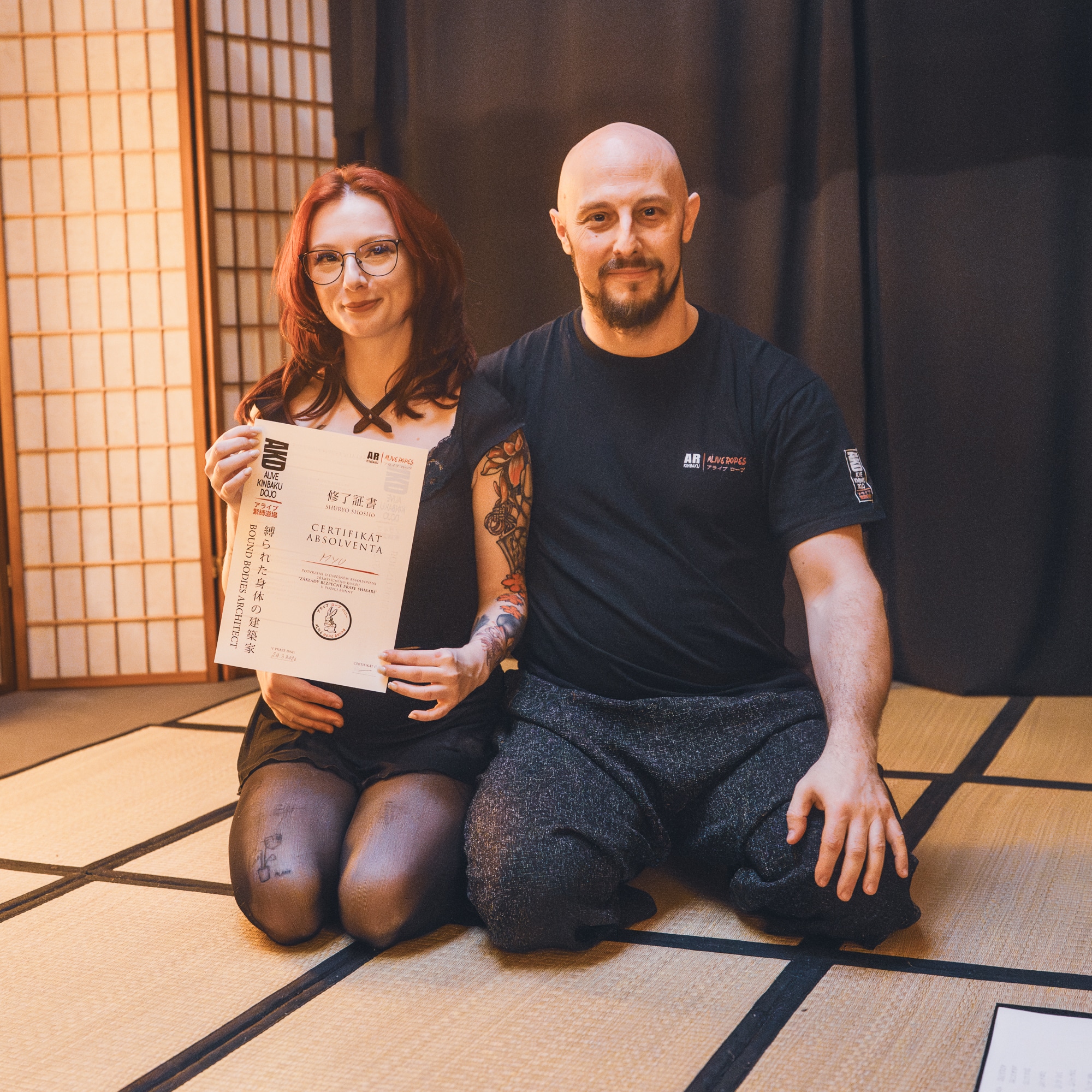 Detail rukou lektora při vázání uzlu na nohou během praxe na tatami.